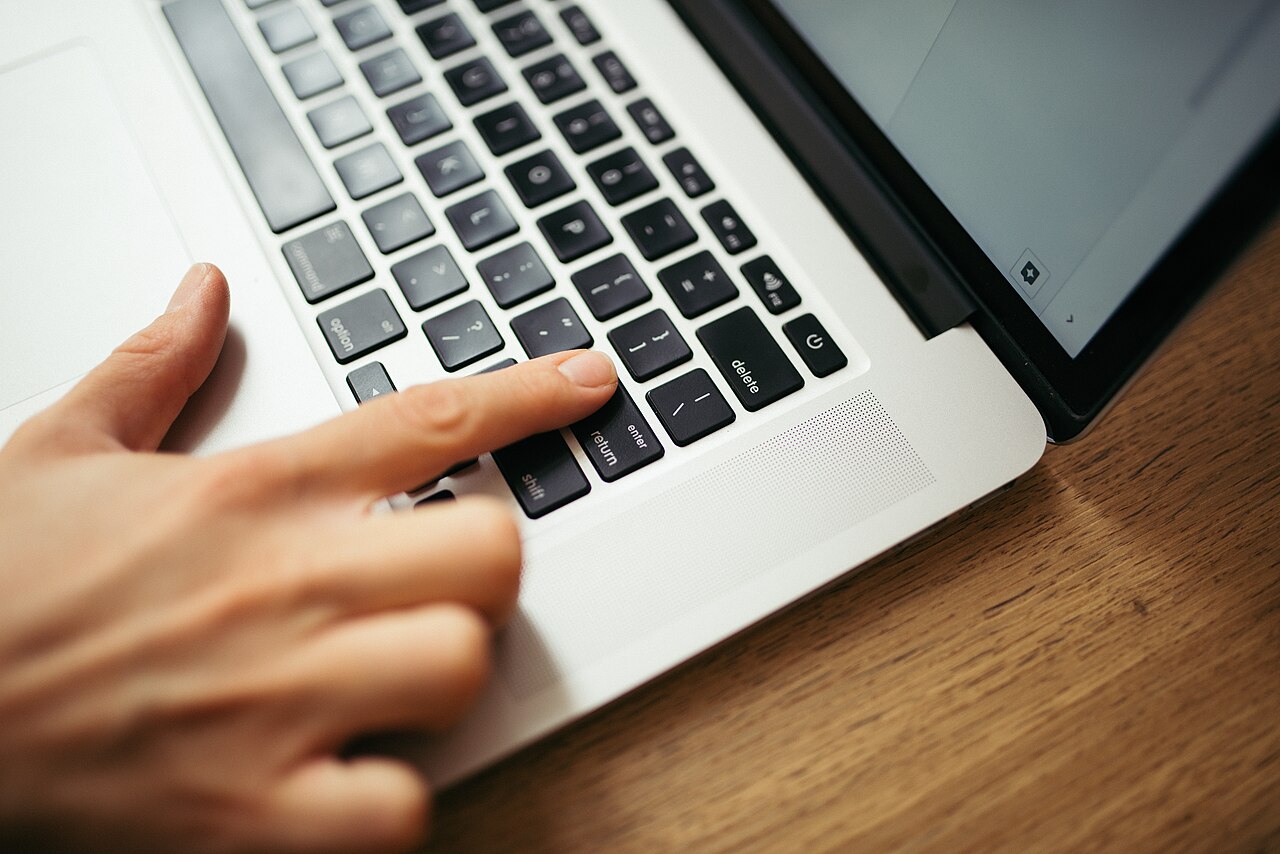 A hand is pressing keys on a laptop keyboard