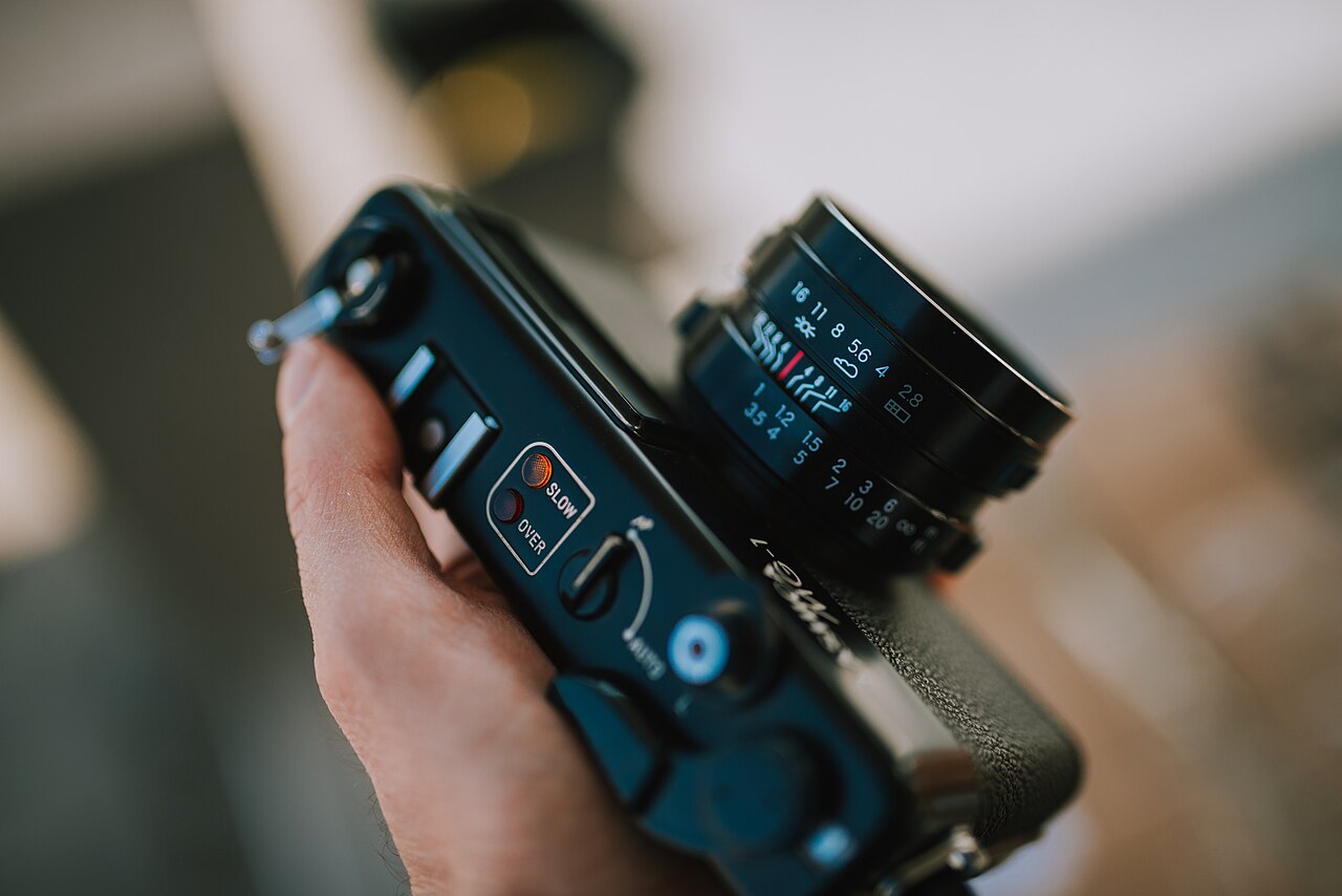 Camera held in hand with focus on lens and controls