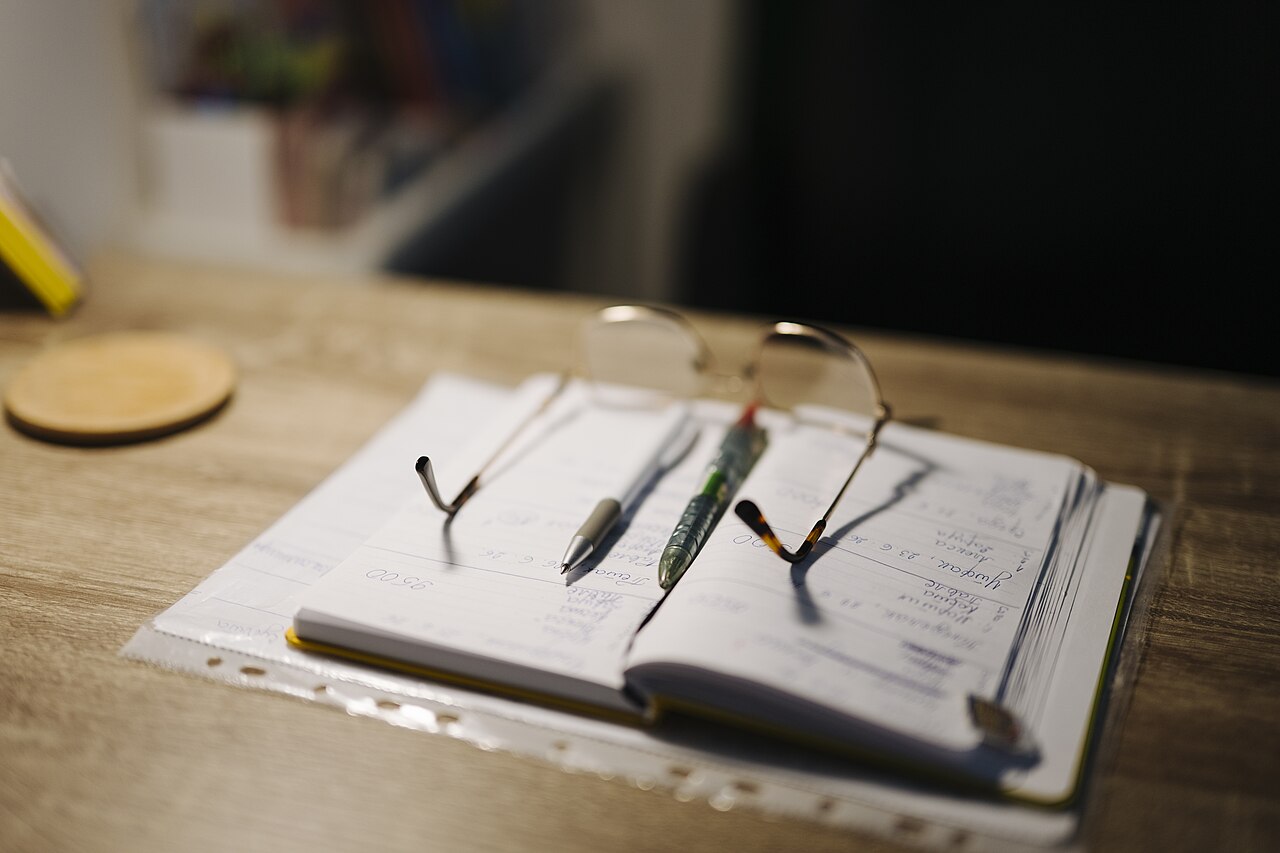 Desk with notebook pens and glasses
