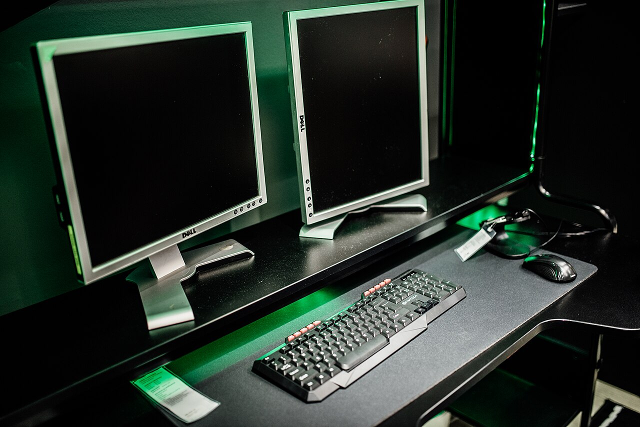 Dual monitor setup in a gaming room with keyboard and mouse in focus