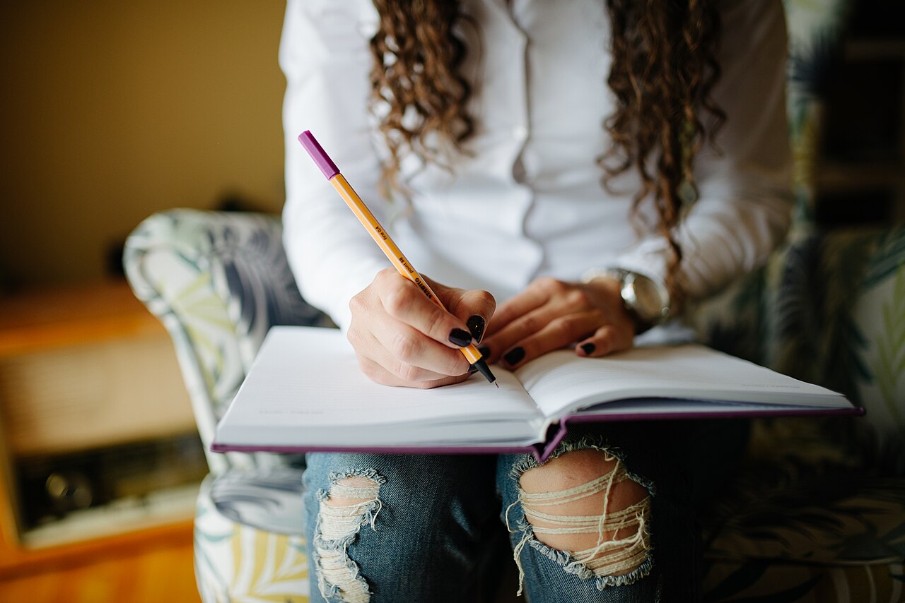 Hands of a woman writing notes in her planner closeup