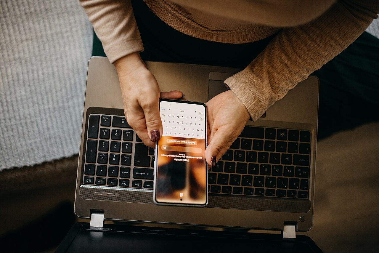 Middle aged woman using a smartphone with laptop