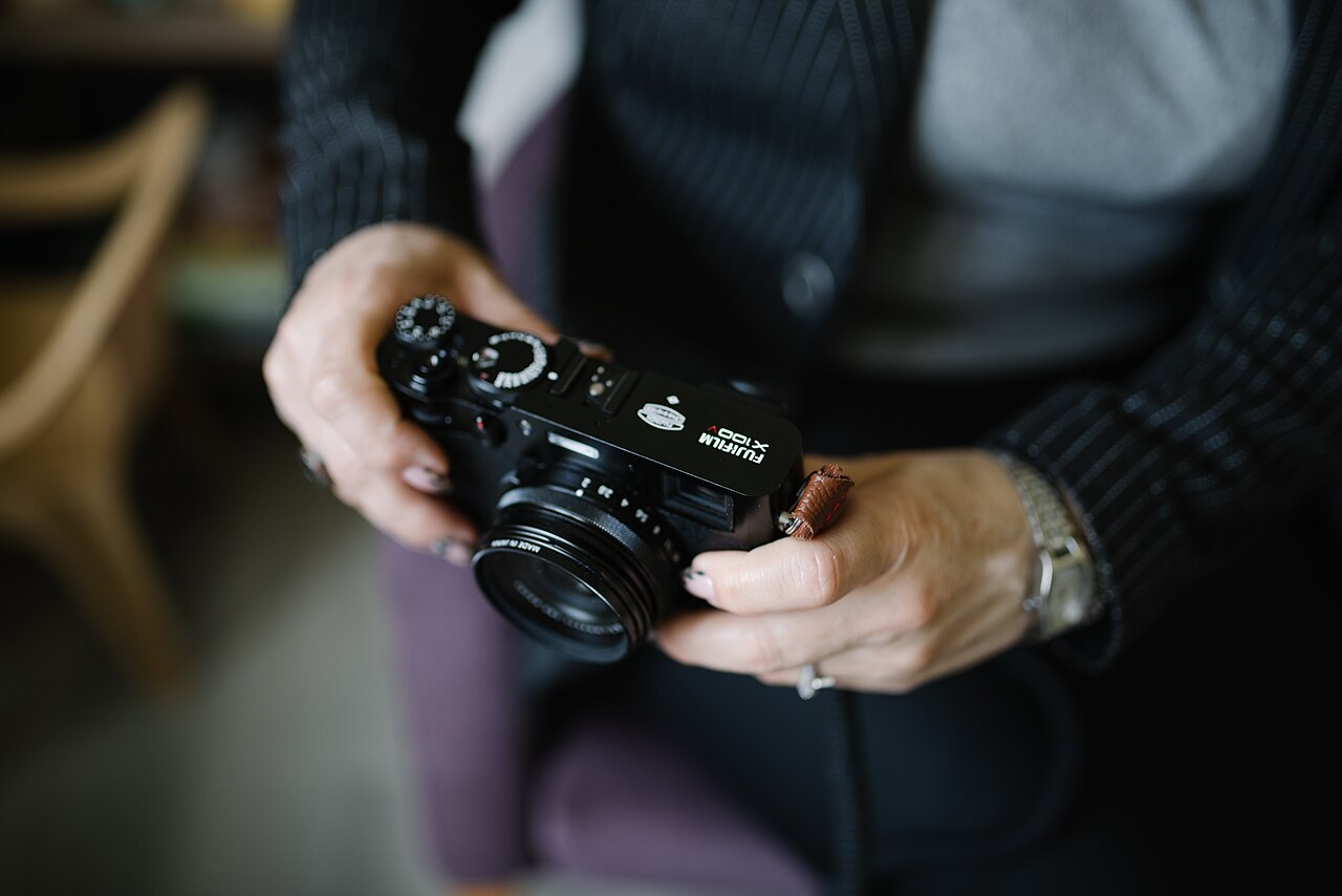 Person holds a modern camera while preparing to capture moments in a cozy indoor setting