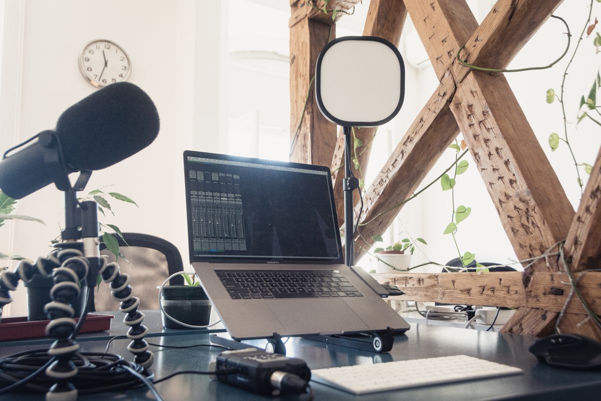 Modern podcast setup featuring a microphone, laptop, and lighting in a home studio.