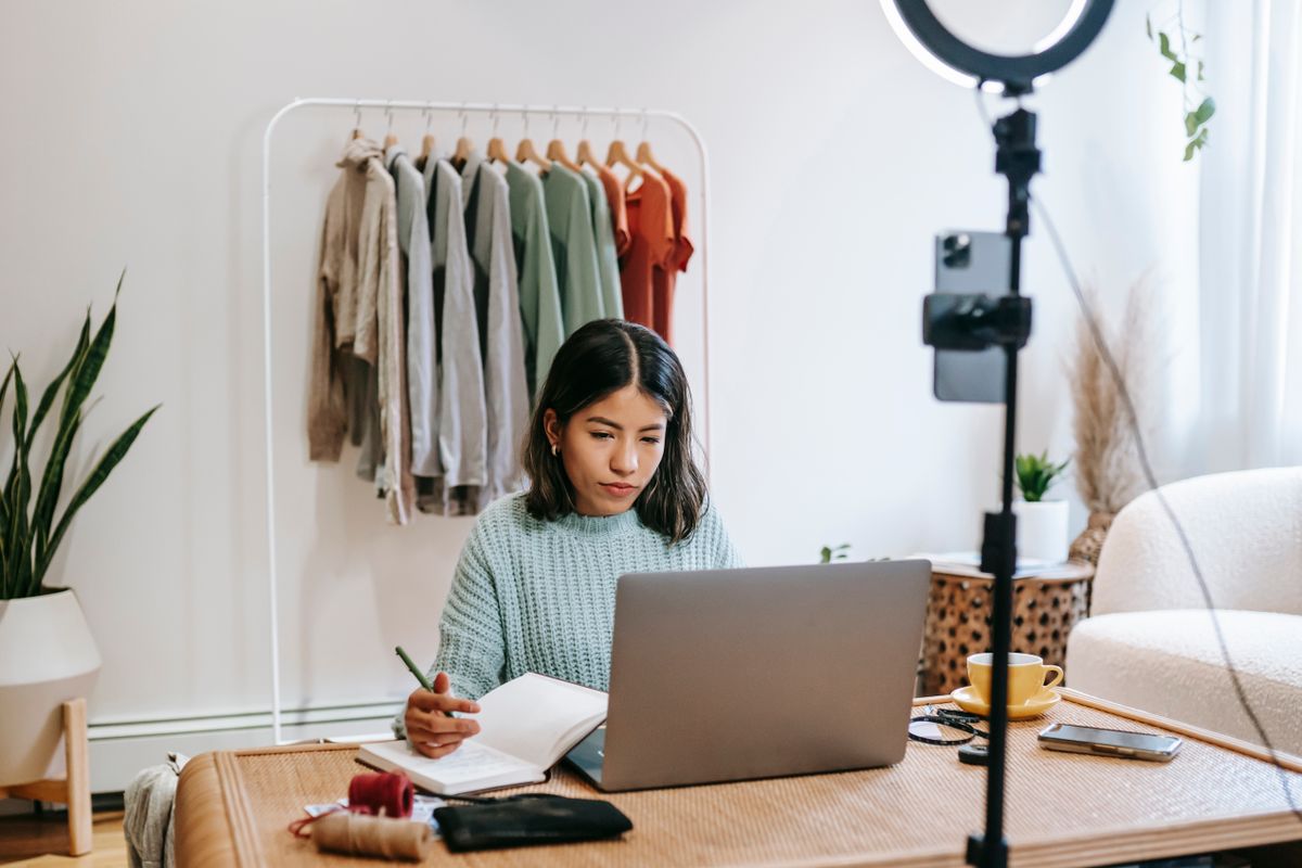 Content creator planning beside a phone camera and laptop